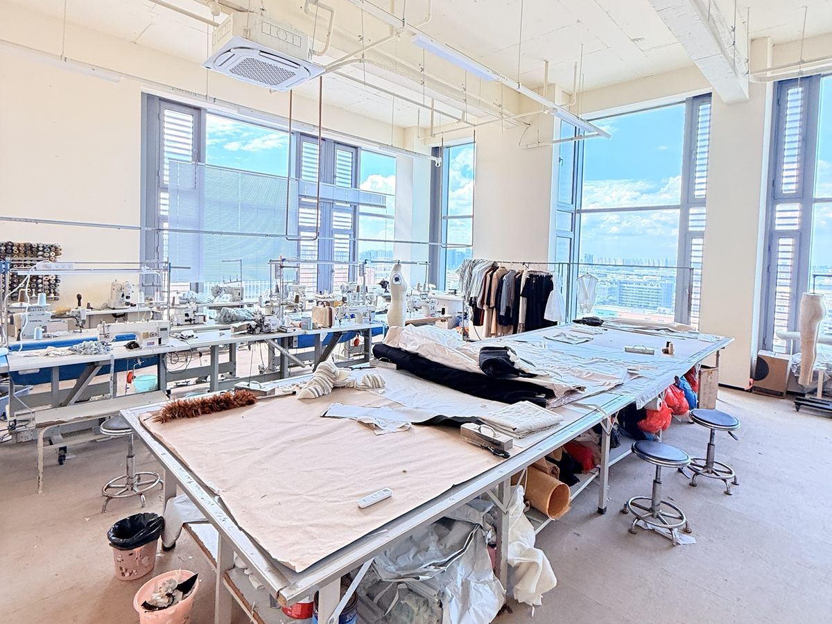 服装设计打样板房，展示裁剪台、缝纫设备和样衣
